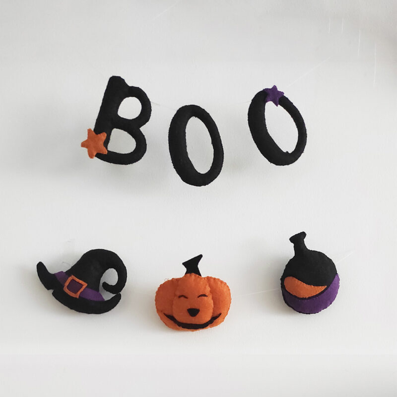 Guirnalda de fieltro para Halloween compuesta por letras BOO, un sombrero, calabaza y poción